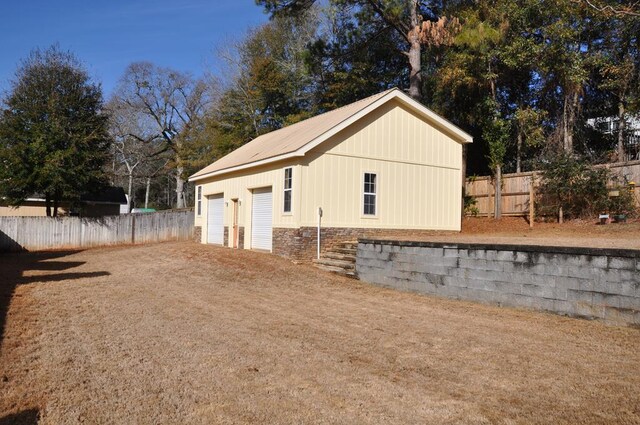 view of side of home featuring a garage and an outbuilding