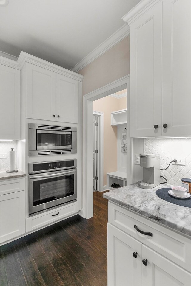 114 Bozeman Way, Dothan, AL 36305 - kitchen with appliances with stainless steel finishes, crown molding, dark wood-type flooring, tasteful backsplash, and white cabinets