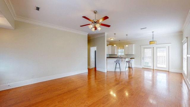 unfurnished living room with crown molding, sink, ceiling fan, and light wood-type flooring