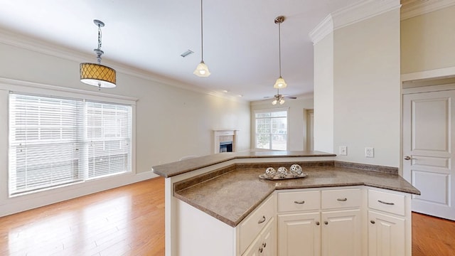 kitchen with white cabinetry, ornamental molding, decorative light fixtures, and kitchen peninsula