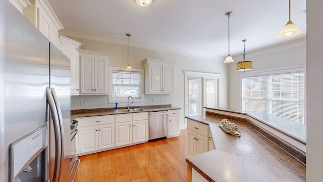 kitchen with stainless steel appliances, white cabinetry, hanging light fixtures, and sink