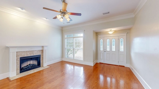 entryway with a tile fireplace, wood-type flooring, ceiling fan, and crown molding