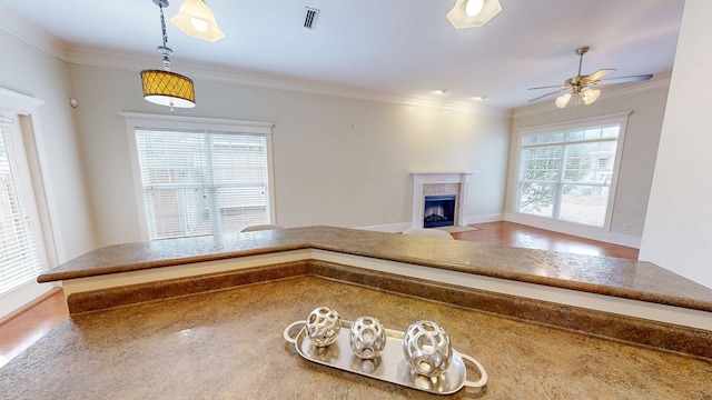 interior space featuring a tiled fireplace, decorative light fixtures, ornamental molding, and ceiling fan