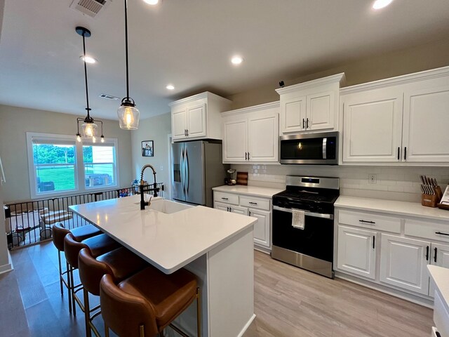 212 Neenan Dr, Enterprise, AL 36330 - kitchen featuring stainless steel appliances, a sink, tasteful backsplash, a center island with sink, and light countertops