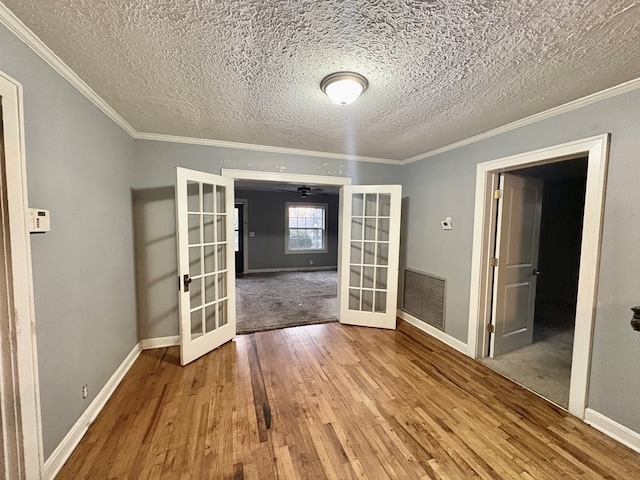 interior space featuring crown molding, french doors, wood-type flooring, and a textured ceiling