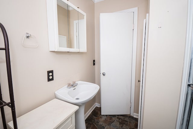 bathroom featuring stone finish flooring, baseboards, and a sink