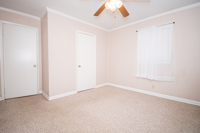 carpeted spare room with ceiling fan, baseboards, and crown molding