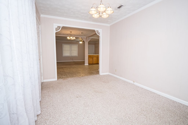 carpeted empty room with a textured ceiling, ornamental molding, visible vents, and a notable chandelier