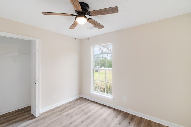 unfurnished bedroom with a closet, visible vents, ceiling fan, light wood-type flooring, and baseboards