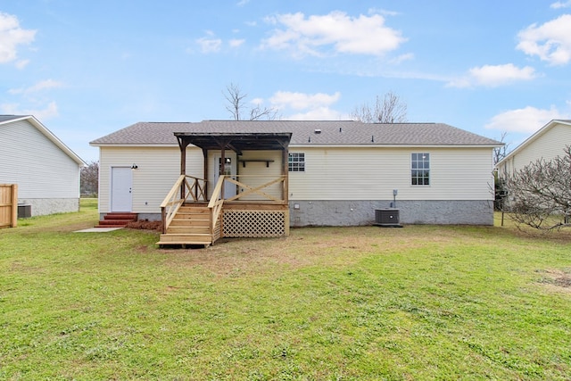 rear view of house with entry steps, a shingled roof, cooling unit, and a yard