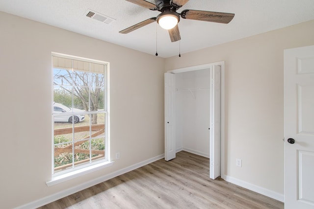 unfurnished bedroom featuring light wood-type flooring, baseboards, visible vents, and a closet