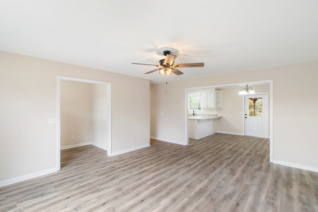 unfurnished living room with light wood-type flooring, ceiling fan, baseboards, and a textured ceiling