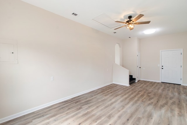 empty room featuring light wood-style floors, baseboards, visible vents, and arched walkways