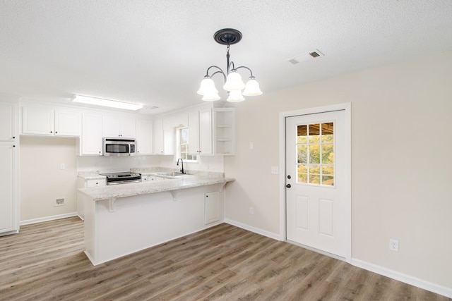 kitchen with visible vents, white cabinets, a peninsula, hanging light fixtures, and stainless steel appliances