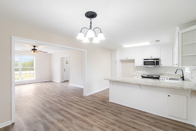 kitchen with pendant lighting, stainless steel appliances, open floor plan, white cabinetry, and a sink