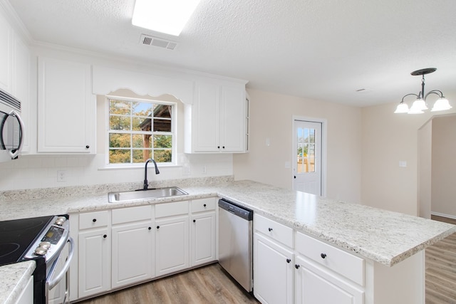 kitchen featuring a peninsula, stainless steel appliances, a sink, light countertops, and pendant lighting