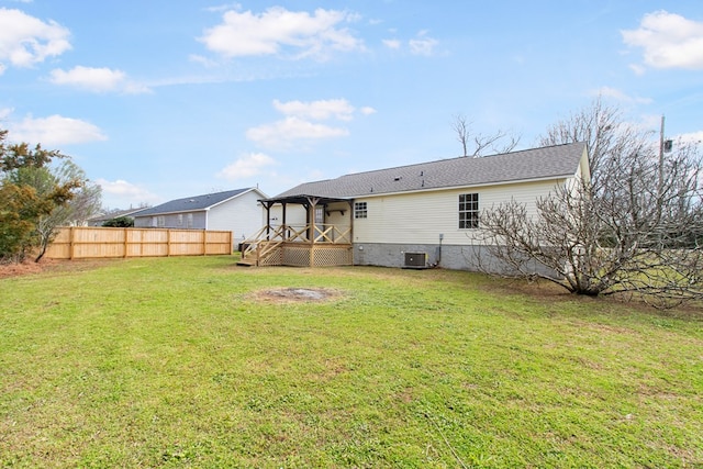 back of property featuring central AC unit, fence, a deck, and a lawn