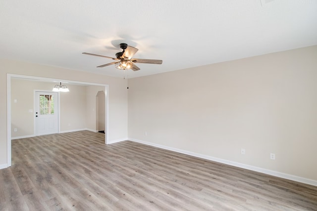 spare room featuring light wood-type flooring, baseboards, a textured ceiling, and ceiling fan with notable chandelier