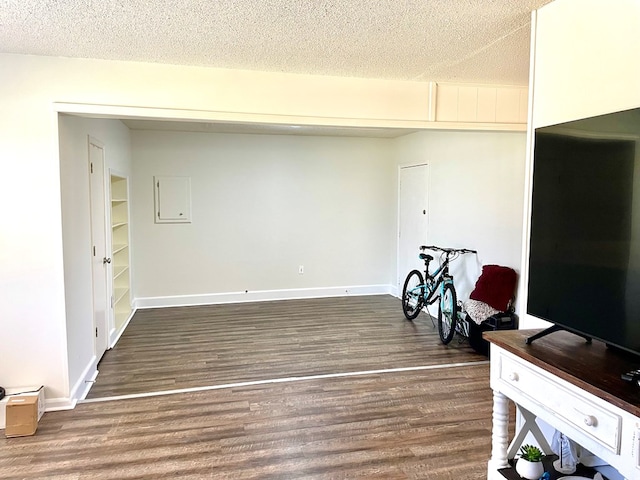 interior space featuring a textured ceiling, baseboards, and wood finished floors