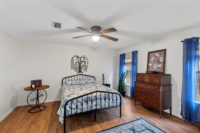 bedroom with ceiling fan, wood-type flooring, and a textured ceiling