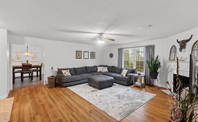 living room with hardwood / wood-style floors, a tile fireplace, a textured ceiling, and ceiling fan