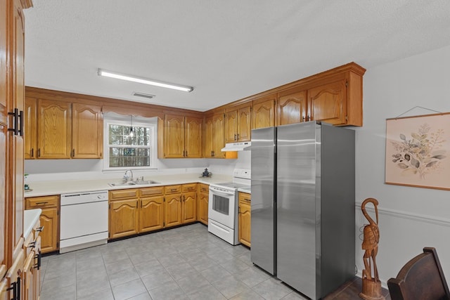 kitchen with white appliances, sink, and a textured ceiling