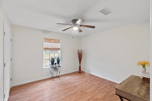 empty room featuring ceiling fan, a textured ceiling, and light wood-type flooring