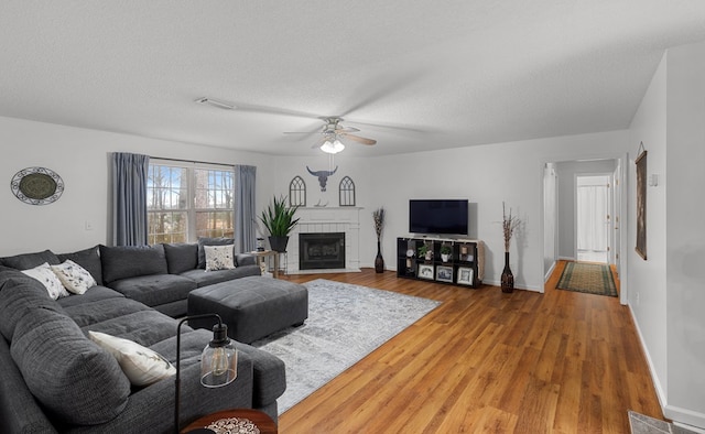 living room with ceiling fan, wood-type flooring, and a textured ceiling