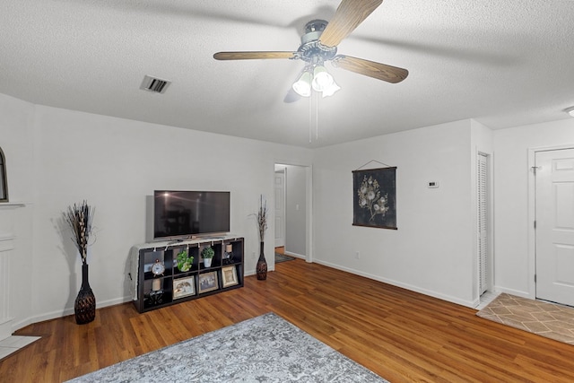 living room with wood-type flooring, ceiling fan, and a textured ceiling