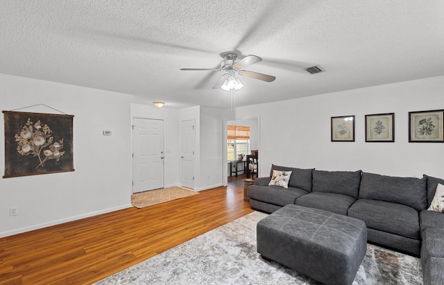 living room featuring wood-type flooring, a textured ceiling, and ceiling fan