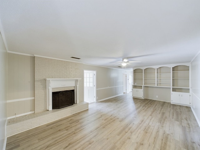 unfurnished living room featuring ceiling fan, light hardwood / wood-style floors, crown molding, and a brick fireplace