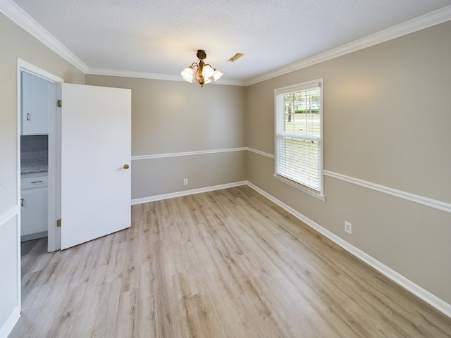 spare room featuring a textured ceiling, light wood-type flooring, crown molding, and an inviting chandelier