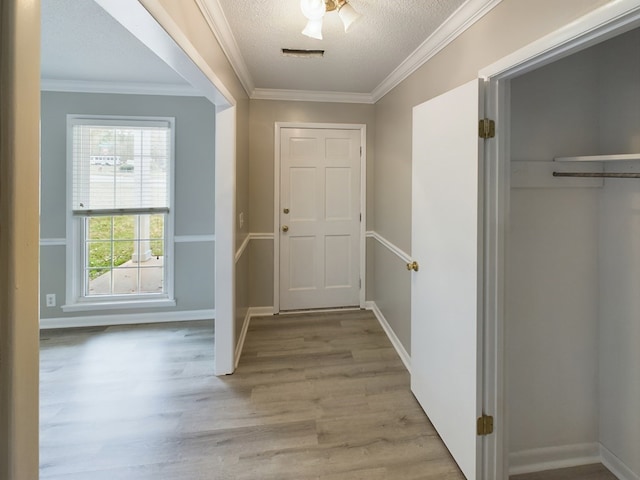 doorway to outside featuring light hardwood / wood-style floors, a textured ceiling, and ornamental molding