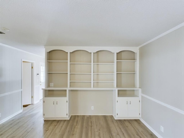 spare room with crown molding, a textured ceiling, and light hardwood / wood-style flooring