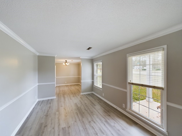 empty room with a textured ceiling, light wood-type flooring, an inviting chandelier, and ornamental molding