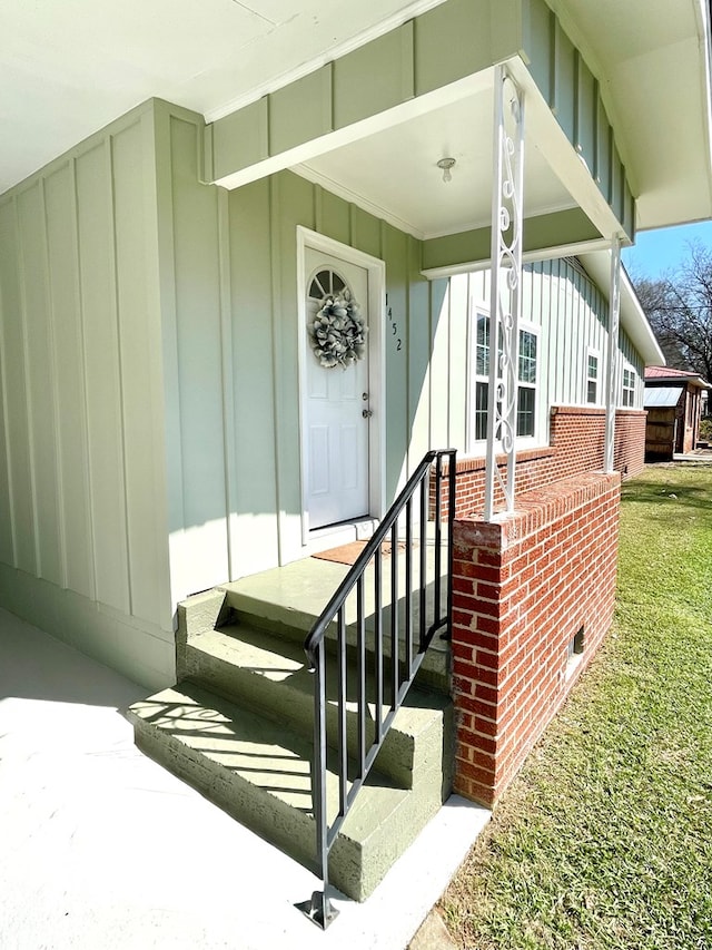 property entrance with board and batten siding and brick siding