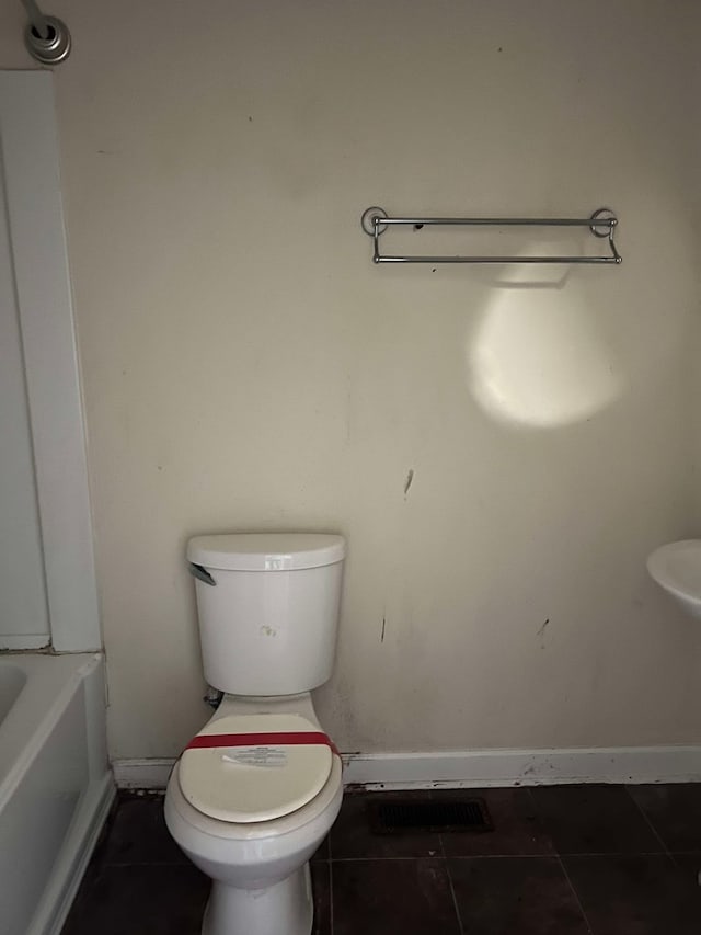 bathroom with toilet, tile patterned flooring, and a bath