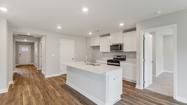 kitchen with white cabinets, stainless steel appliances, a center island with sink, and sink