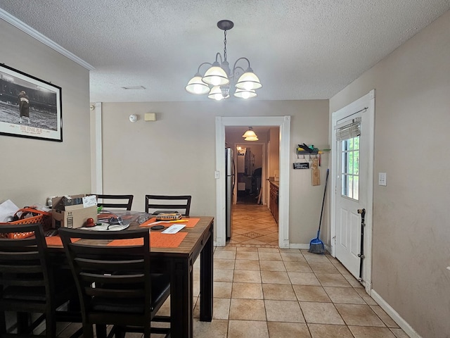 dining room with a textured ceiling, light tile patterned floors, a notable chandelier, and baseboards