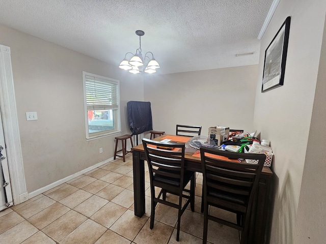 dining room featuring a chandelier, a textured ceiling, light tile patterned flooring, and baseboards