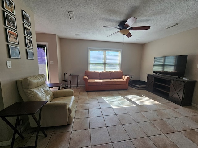 tiled living area with baseboards, visible vents, a textured ceiling, and a ceiling fan