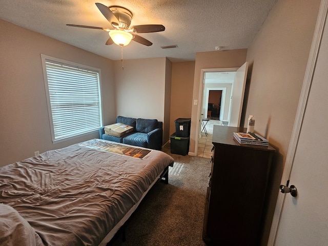 carpeted bedroom featuring visible vents, a textured ceiling, and a ceiling fan