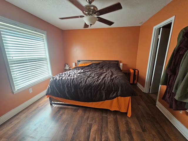bedroom with a textured ceiling, baseboards, and wood finished floors