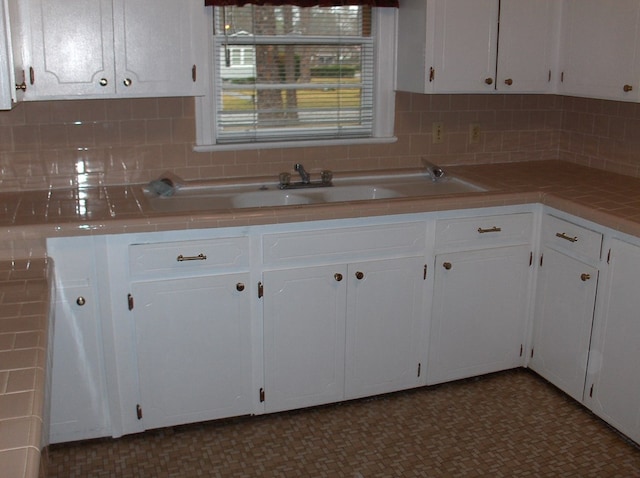 kitchen with decorative backsplash, tile countertops, and white cabinetry