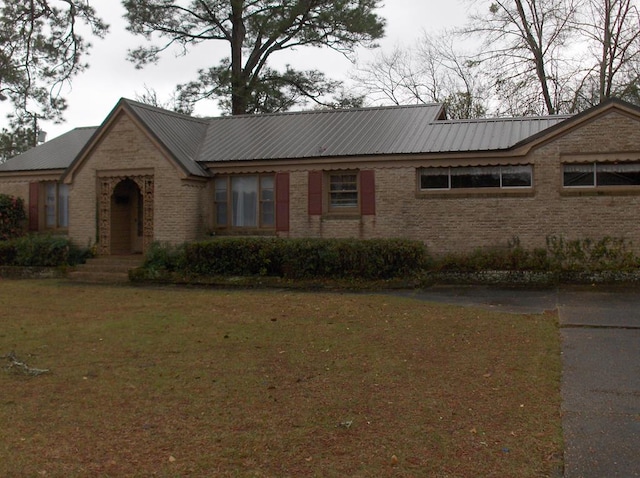 ranch-style house featuring brick siding, metal roof, and a front yard