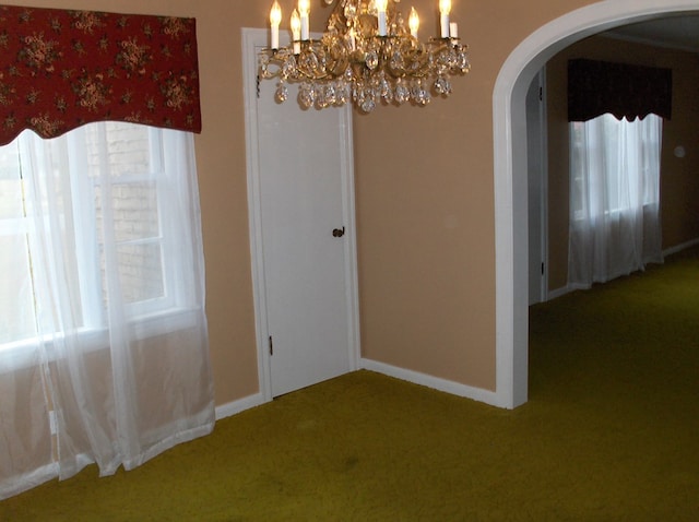 unfurnished dining area featuring baseboards, plenty of natural light, arched walkways, and carpet flooring