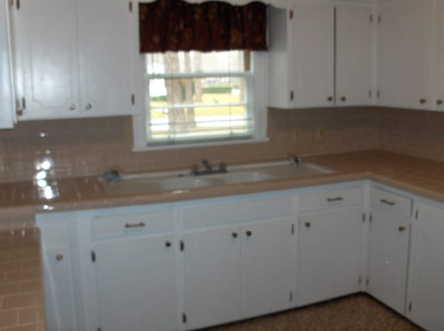 kitchen with white cabinetry, light countertops, and backsplash