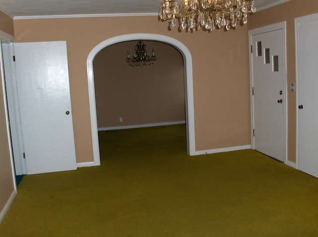 unfurnished dining area with crown molding, carpet flooring, baseboards, and arched walkways