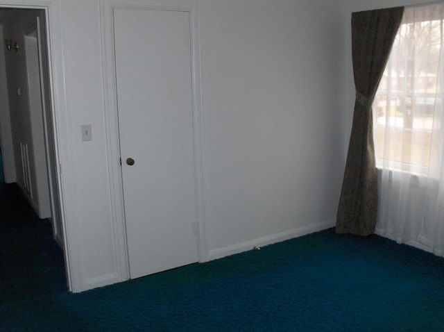 interior space with baseboards and dark colored carpet