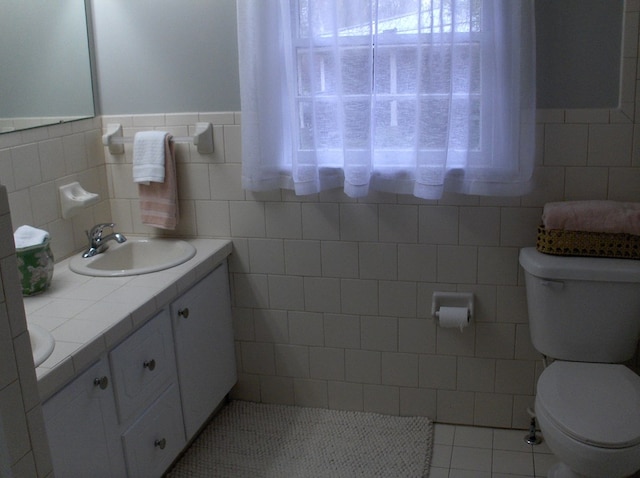 bathroom featuring tile patterned floors, toilet, tile walls, and vanity